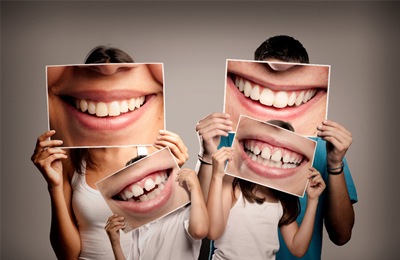 A family holding pictures of smiles in front of their faces