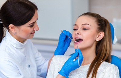 A dentist checking a female patient’s mouth