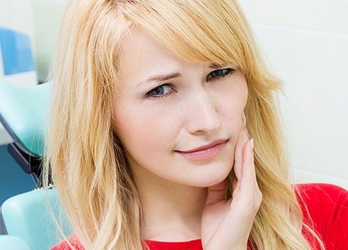 blonde woman holding cheek in pain