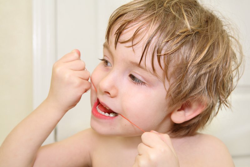 Little boy flossing his teeth